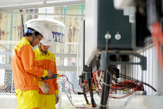 Two technicians with helmets working on electrical equipment outdoors, ensuring safety. A working brief on electrical contractor expansion